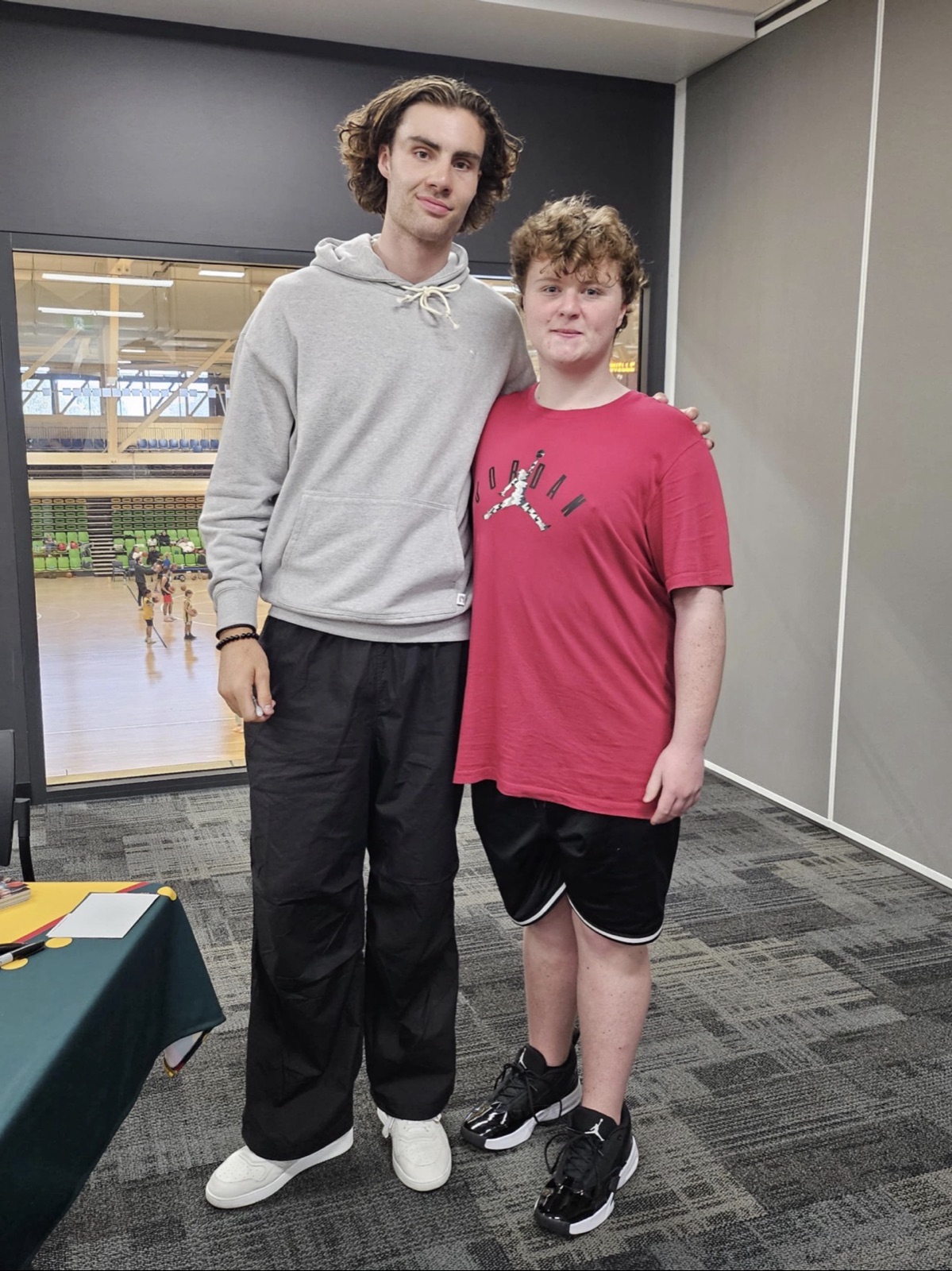Posing with a basketball player in the stadium foyer, arm around the shoulder