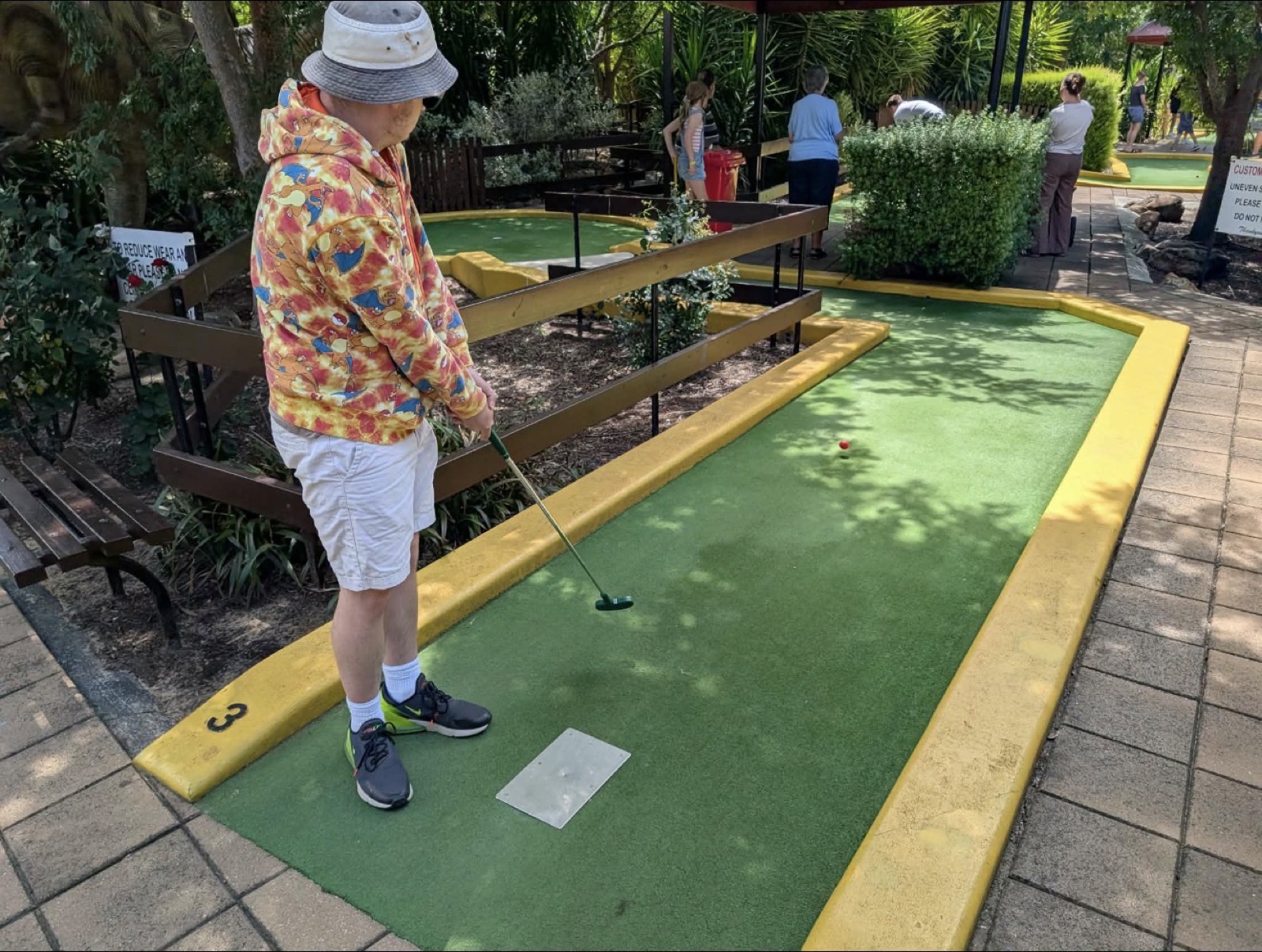 Mid swing on the mini golf course on a sunny day out